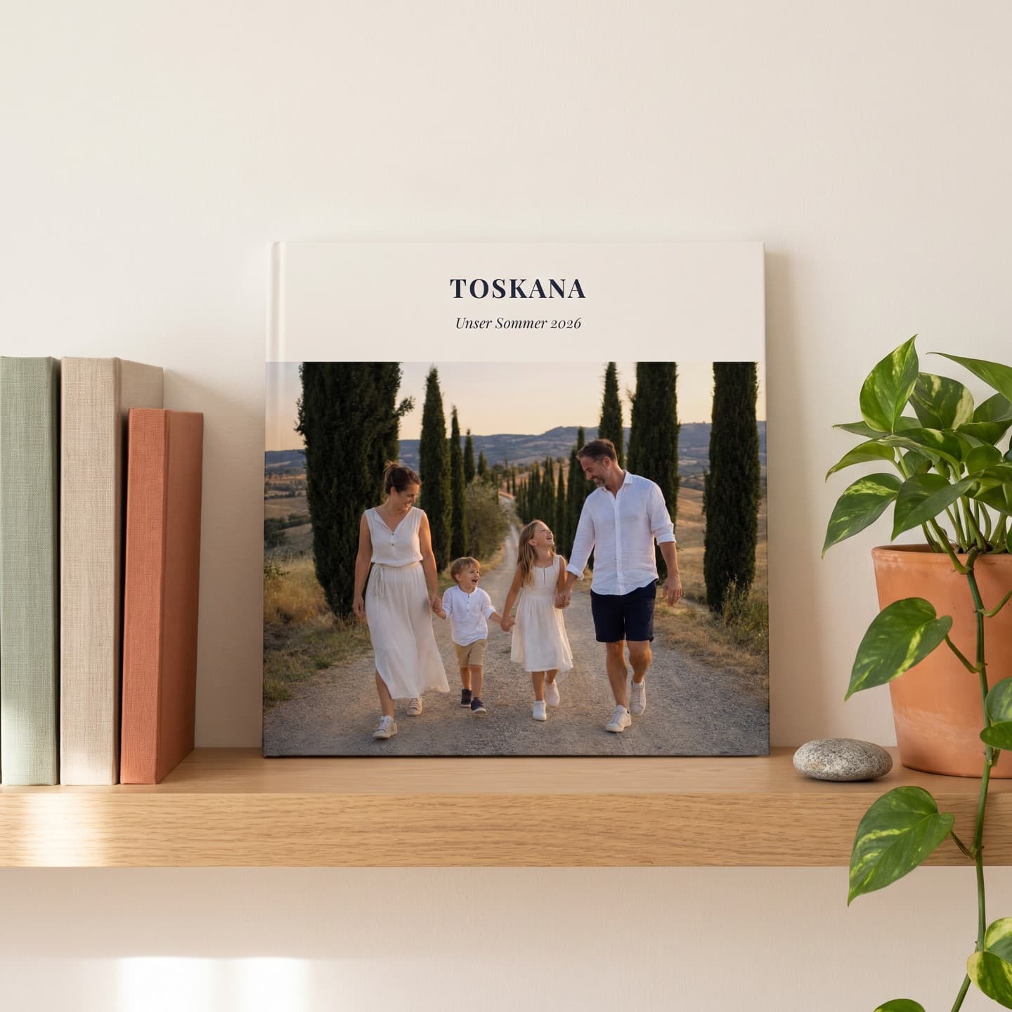Reisefotobuch „Toskana" im Wandregal neben Büchern und einer Pflanze
