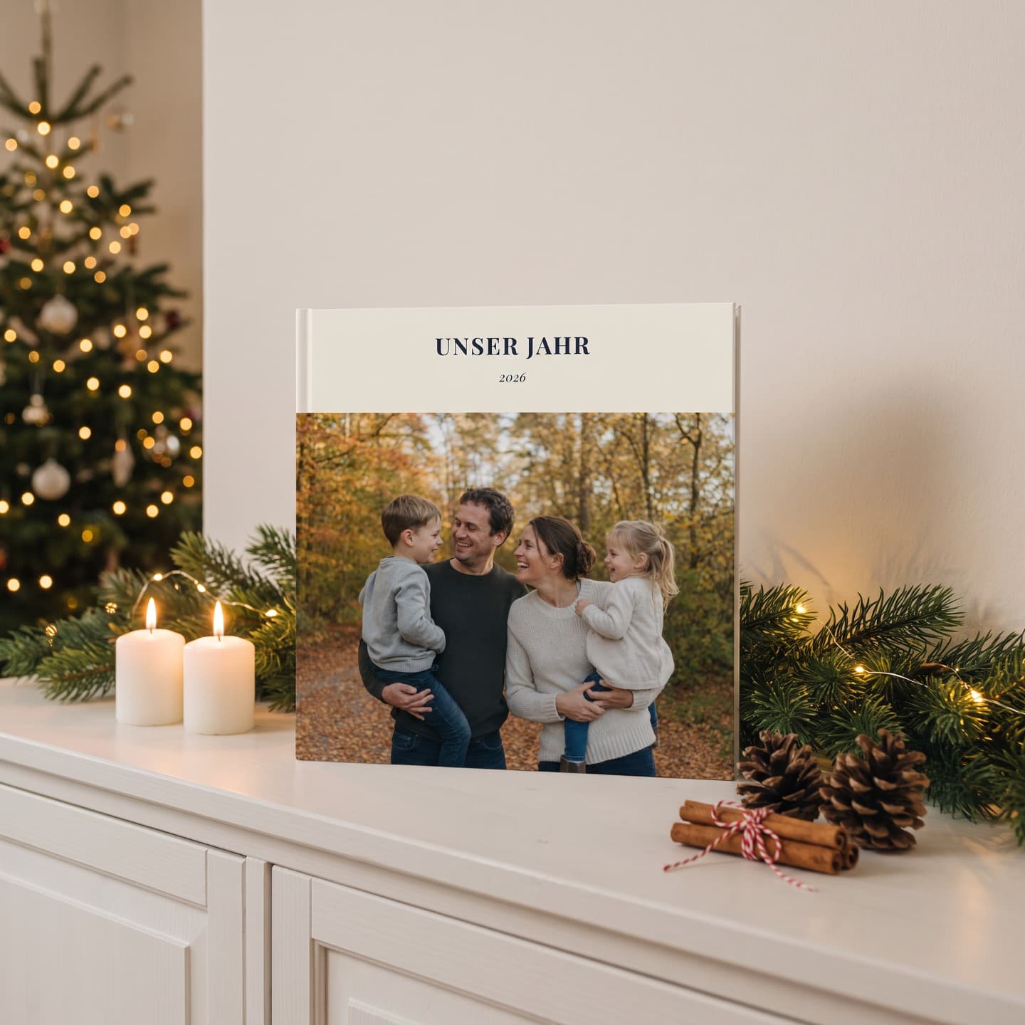 Fotobuch „Unser Jahr" auf der Kommode zwischen Kerzen, Tannengrün und einem Geschenk